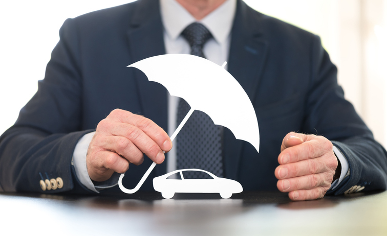 Man in suit holding a cartoon umbrella over a cartoon car to represent auto insurance coverage