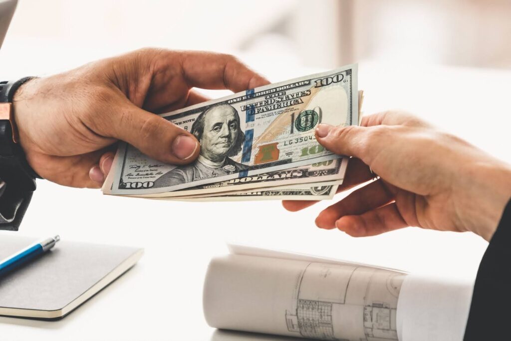 Cash transferring hands with floor plans visible on a table to represent compensation for property damage