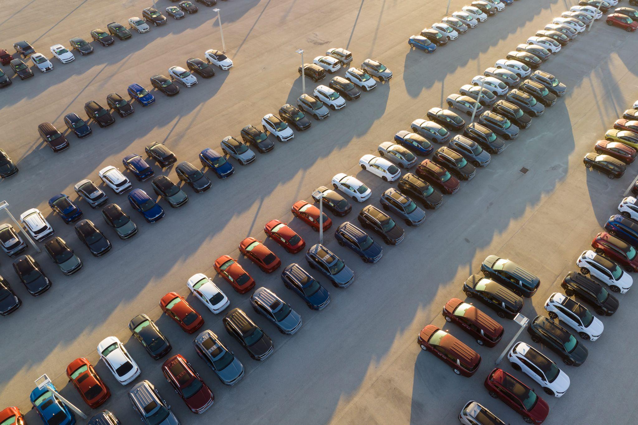 Large parking lot of auto dealer with many brand new cars parked for sale